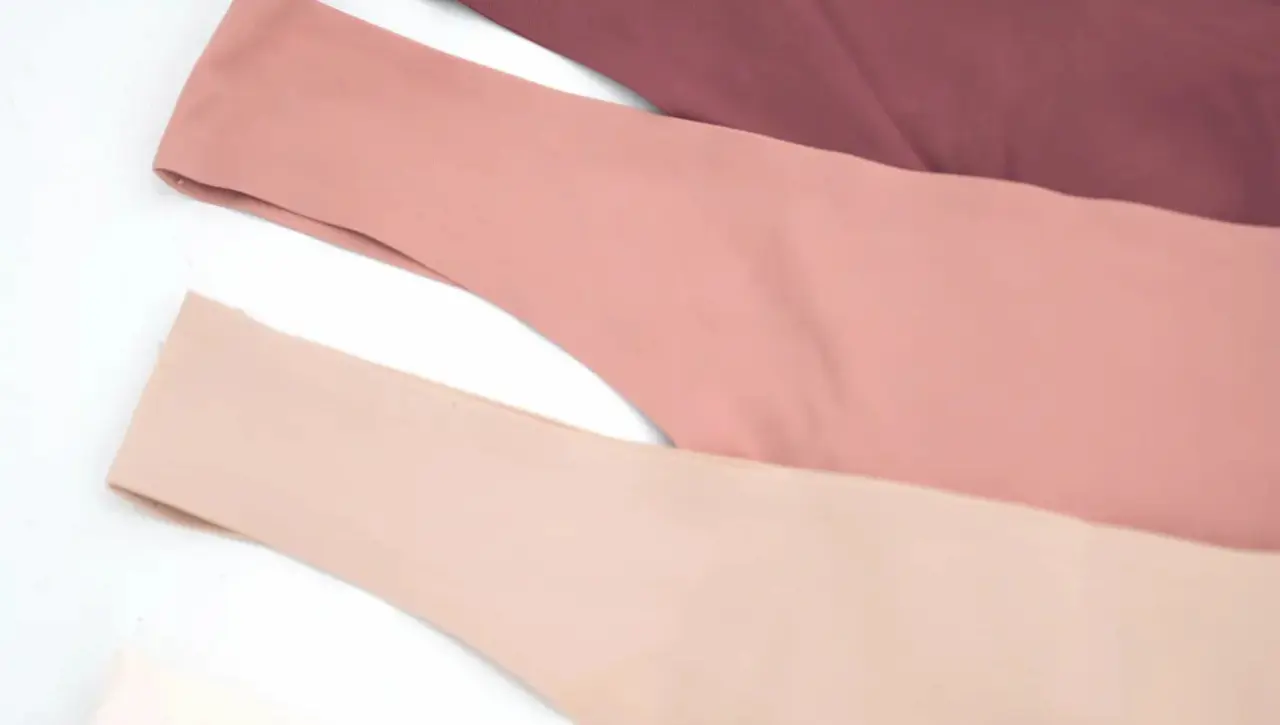 Close-up van drie Philotes lingerie setjes in verschillende kleuren: bordeaux, roze en nude.